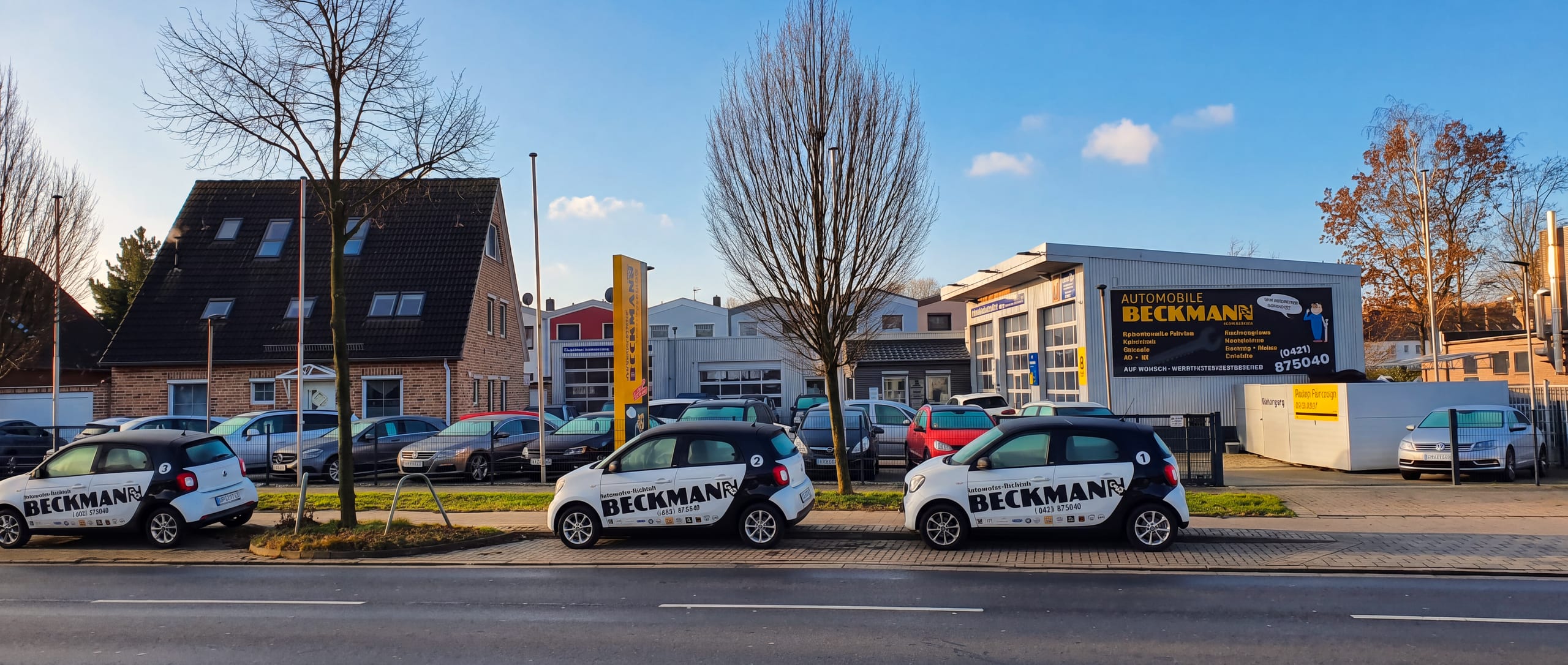 Automobile Beckmann am Arsterdamm 85, von der Straße aus gesehen, davor zwei Firmenfahrzeuge